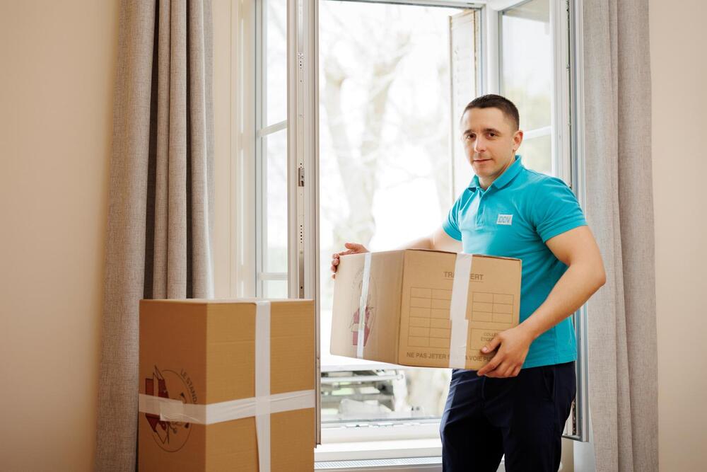 Un déménageur de la société Du Vexin Déménagement portant d'un carton pour le déposer au nouveau domicile du client déménagé. Un déménageur de la société Du Vexin Déménagement portant d'un carton pour le déposer au nouveau domicile du client déménagé.