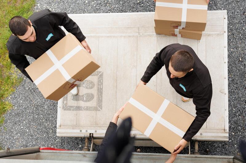 Trois de nos déménageurs portent des cartons pleins pour les entreposer dans notre garde-meubles